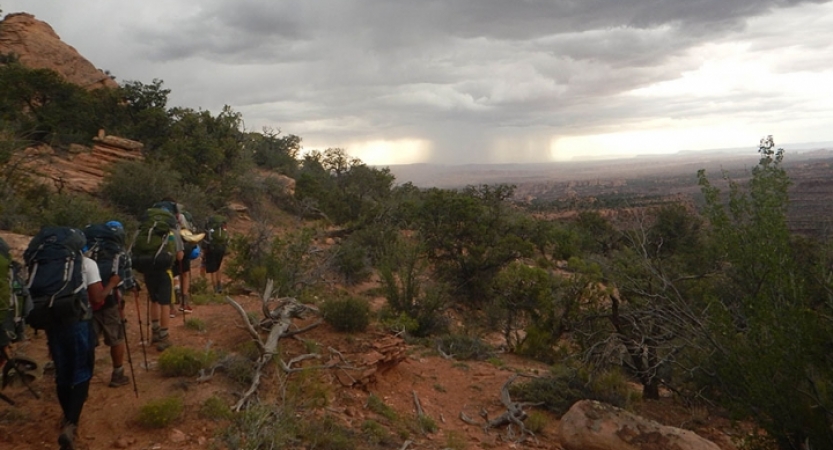 a group of backpackers make their way through a desert landscape on an outward bound course